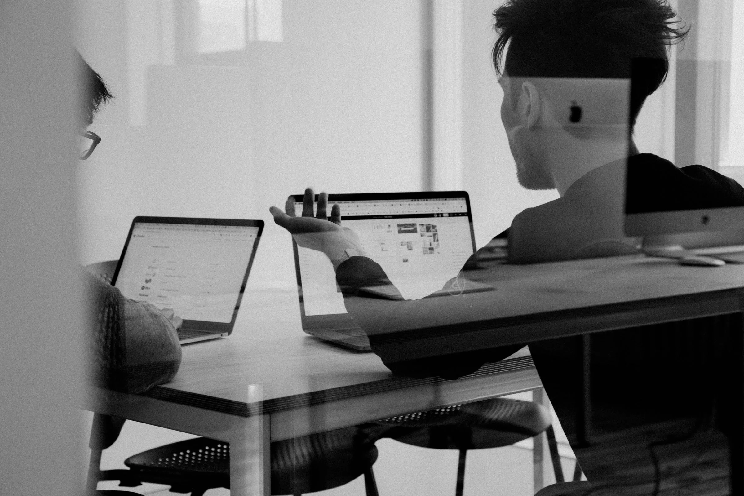 People working at laptops around a table, in black and white