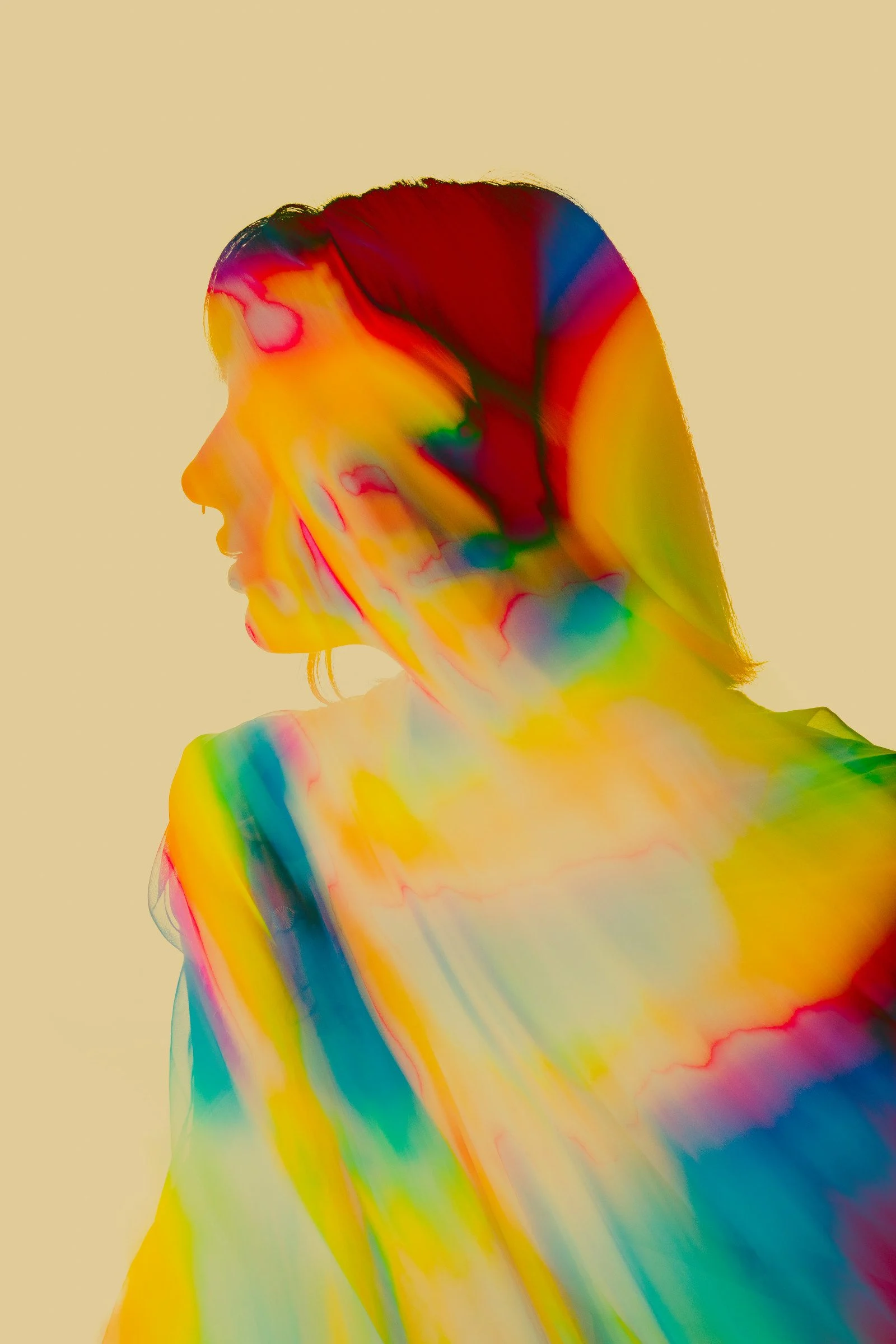 Profile of a woman in a rainbow of overlapping colours against a pale background
