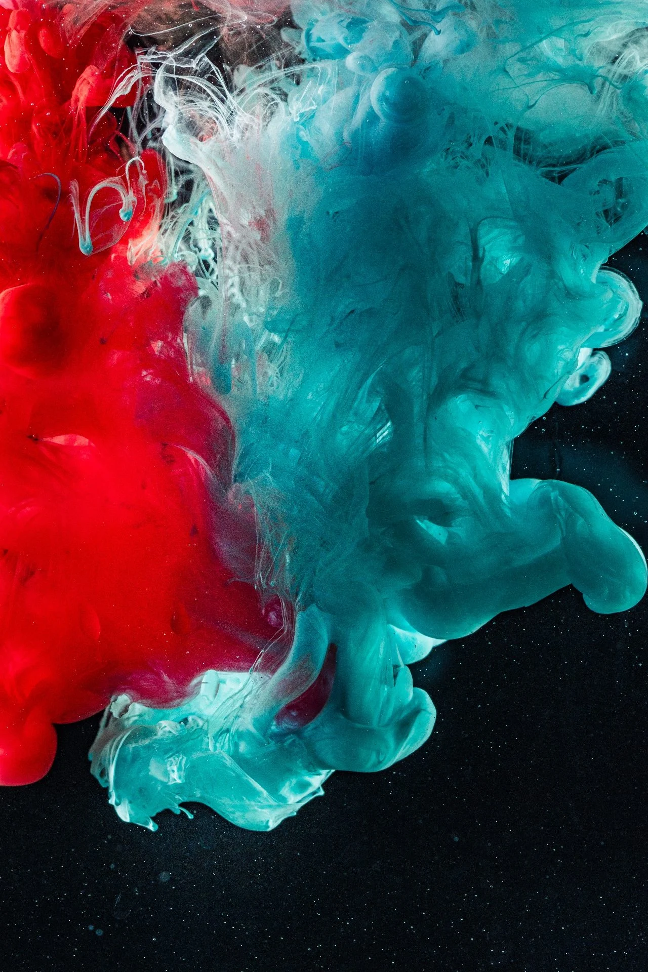 Clouds of red and teal ink swirling against black